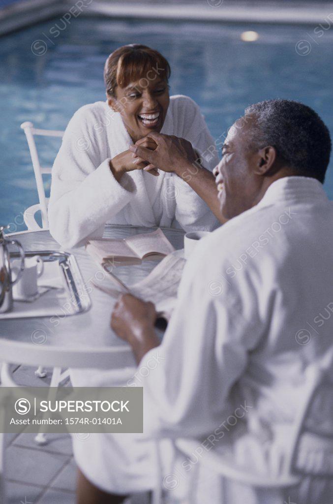 Stock Photo: 1574R-01401A Couple sitting beside a swimming pool