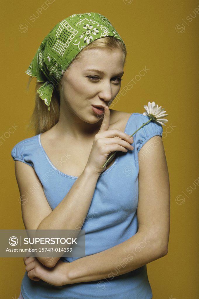 Stock Photo: 1574R-014399 Portrait of a teenage girl holding a flower with a finger on her lips