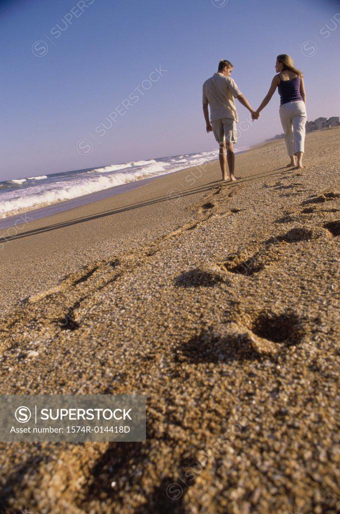 Stock Photo: 1574R-014418D Rear view of a young couple walking together on the beach