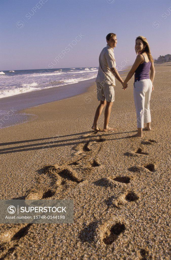 Stock Photo: 1574R-014419B Rear view of a young couple walking on the beach