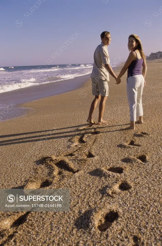 Rear view of a young couple walking on the beach