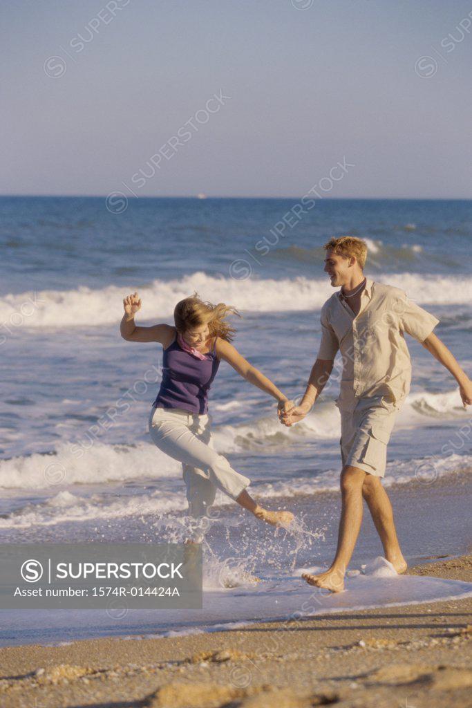 Stock Photo: 1574R-014424A Teenage couple holding hands and walking on the beach
