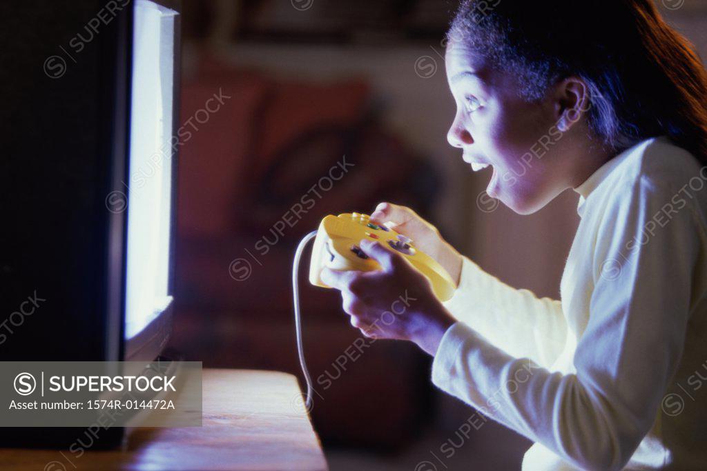 Stock Photo: 1574R-014472A Side profile of a teenage girl playing video games