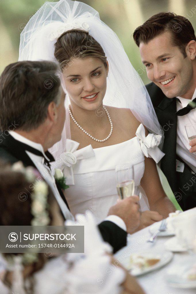 Stock Photo: 1574R-014492A Newlywed couple sitting with their parent and a flower girl