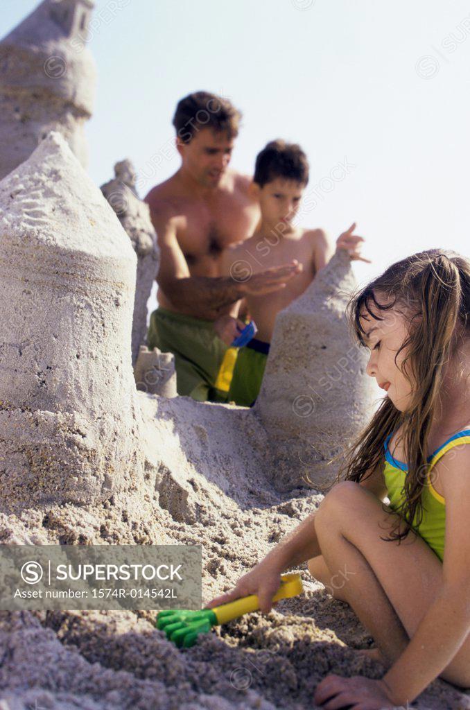 Stock Photo: 1574R-014542L Father making a sand castle on the beach with his son and daughter