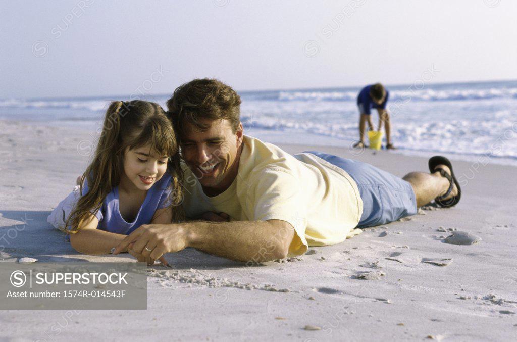 Stock Photo: 1574R-014543F Father and his daughter writing in sand on the beach