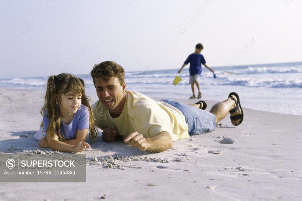 Stock Photo: 1574R-014543Q Father and his daughter writing in sand on the beach