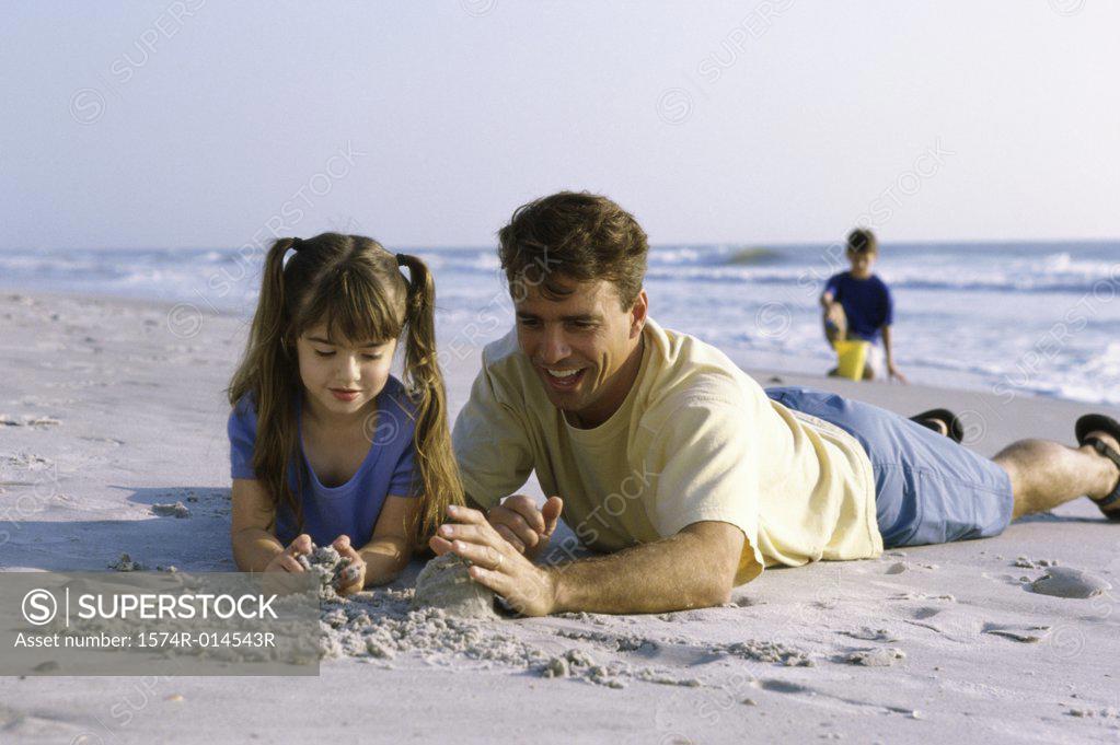 Stock Photo: 1574R-014543R Father and his daughter making a sand castle on the beach
