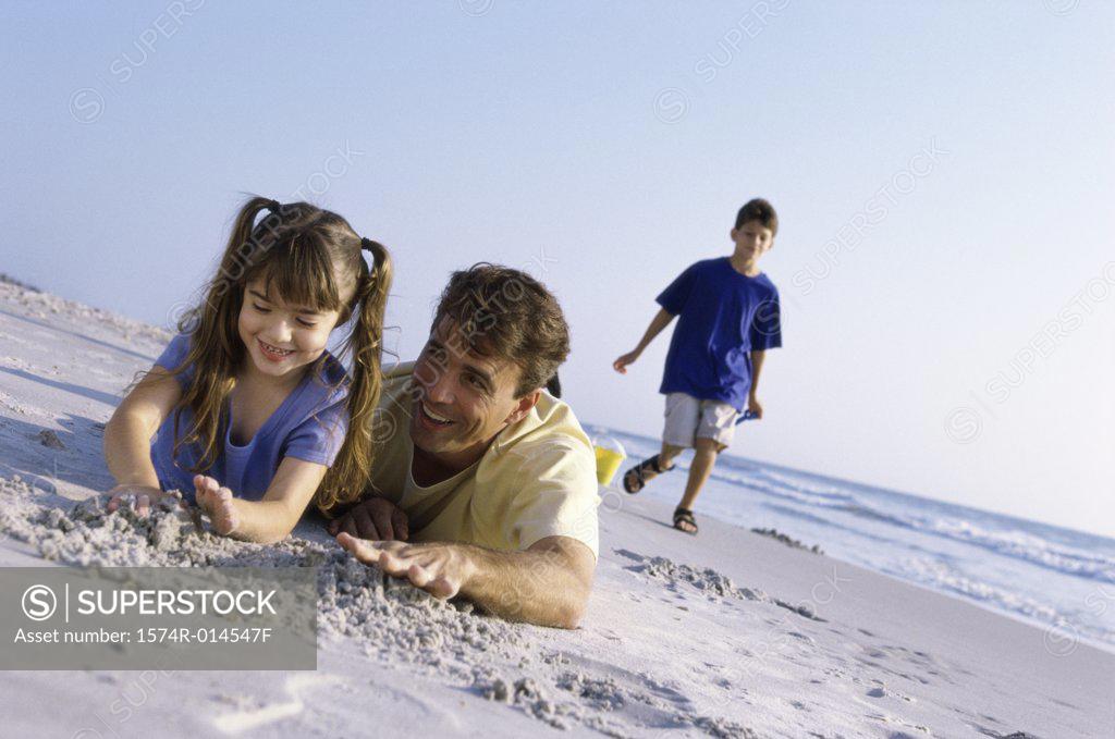 Stock Photo: 1574R-014547F Father with his daughter making a sand castle on the beach