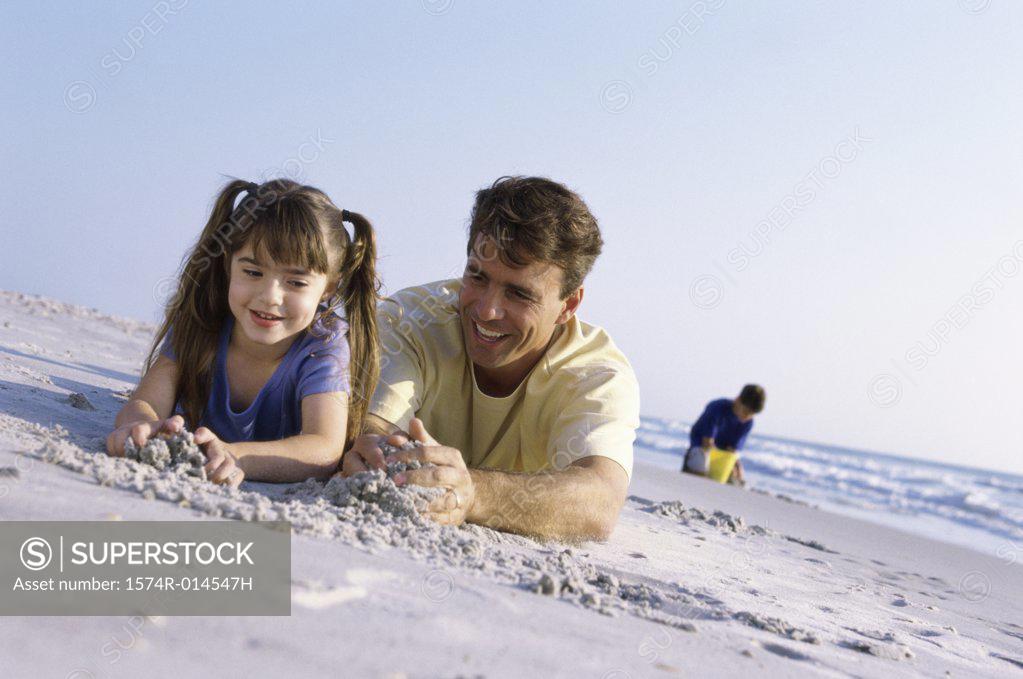 Stock Photo: 1574R-014547H Father with his daughter making a sand castle on the beach