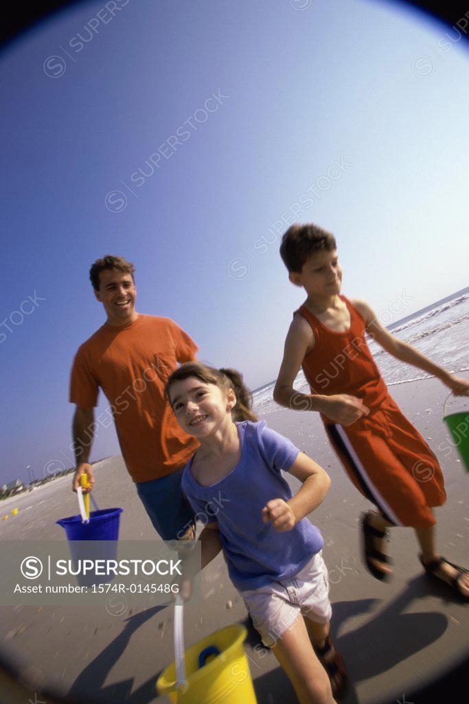 Stock Photo: 1574R-014548G Father with his son and daughter running on the beach