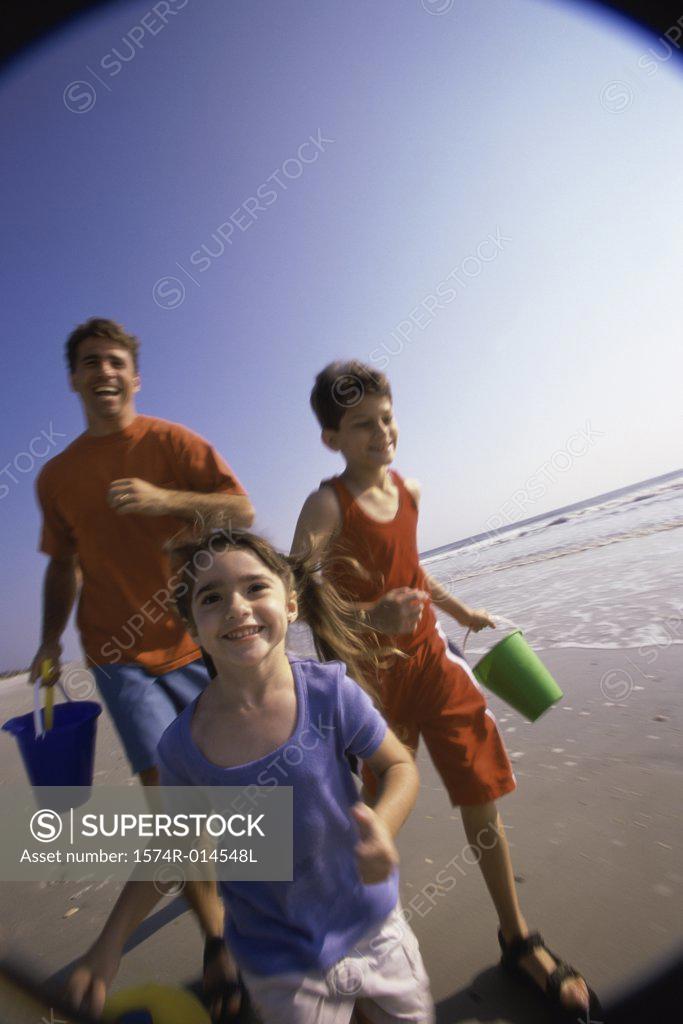 Stock Photo: 1574R-014548L Father with his son and daughter running on the beach