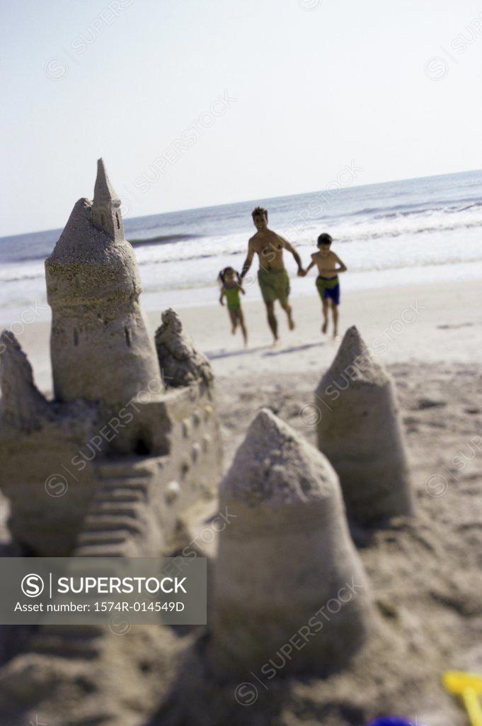 Stock Photo: 1574R-014549D Father with his son and daughter running on the beach