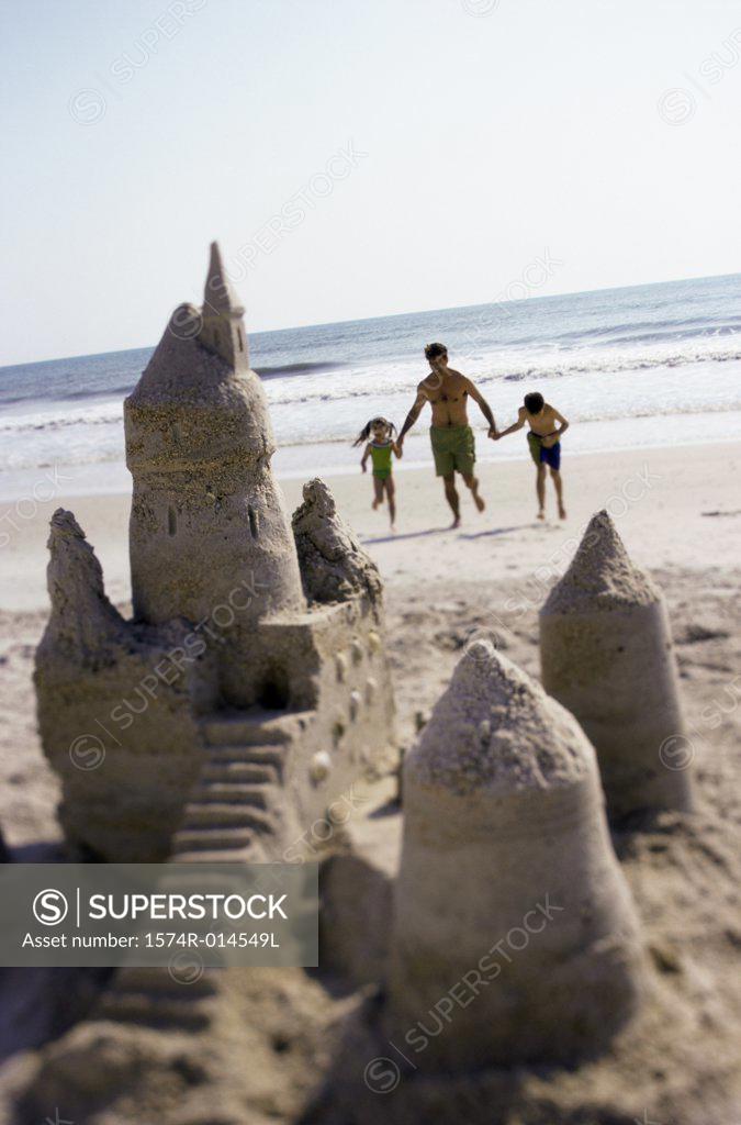 Stock Photo: 1574R-014549L Father with his son and daughter running on the beach
