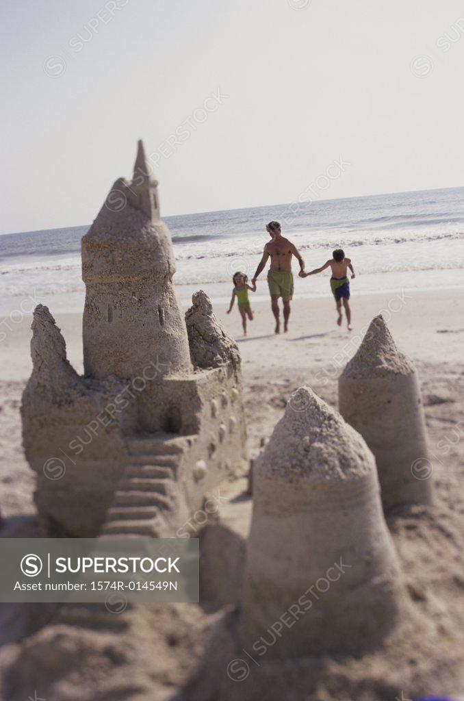 Stock Photo: 1574R-014549N Father with his son and daughter running on the beach