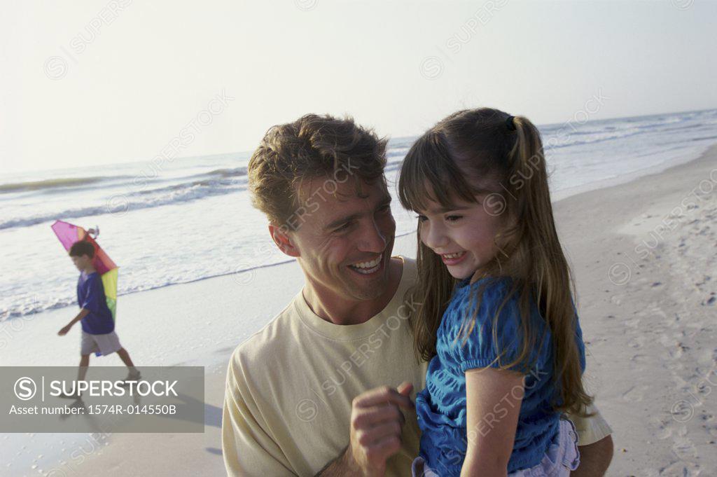 Stock Photo: 1574R-014550B Father carrying his daughter on the beach