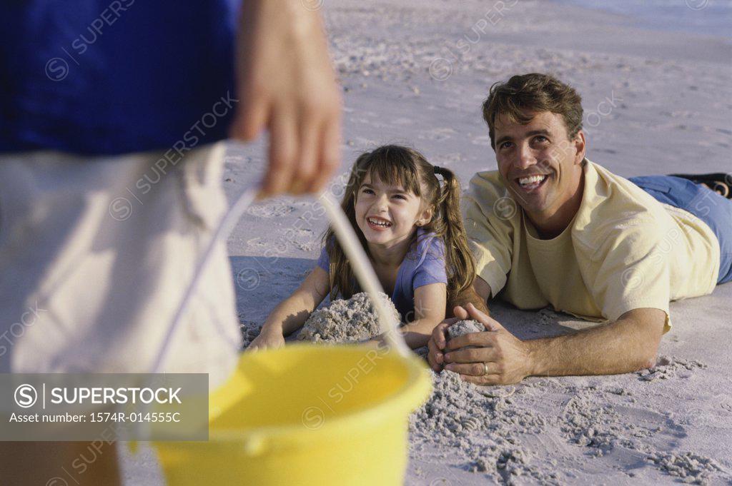 Stock Photo: 1574R-014555C Father with his daughter making a sand castle on the beach