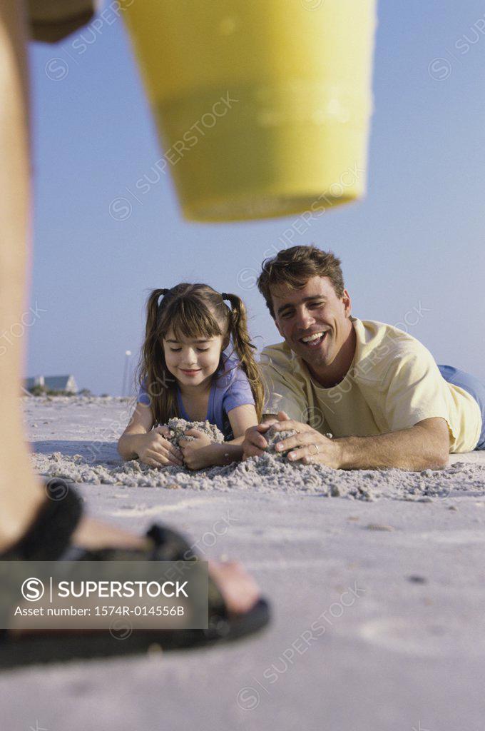 Stock Photo: 1574R-014556B Father and daughter making a sand castle on the beach