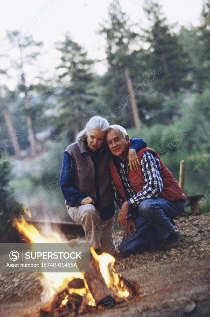 Stock Photo: 1574R-01455A Senior couple together near a campfire in the woods