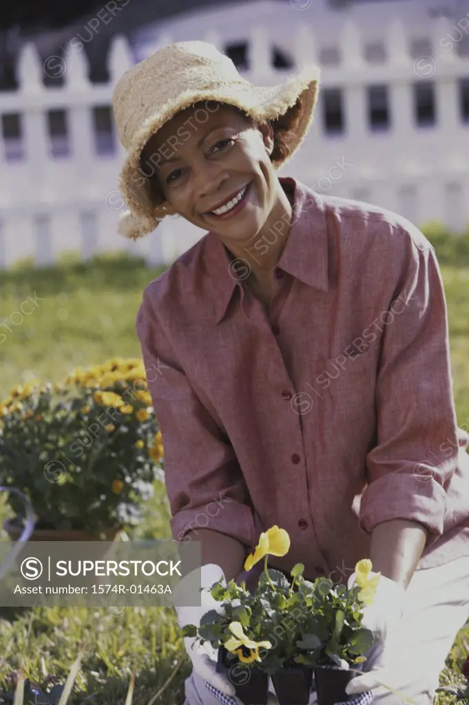 Portrait of a senior woman holding potted plants