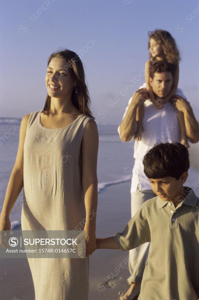Stock Photo: 1574R-014657C Parents and their two children walking on the beach