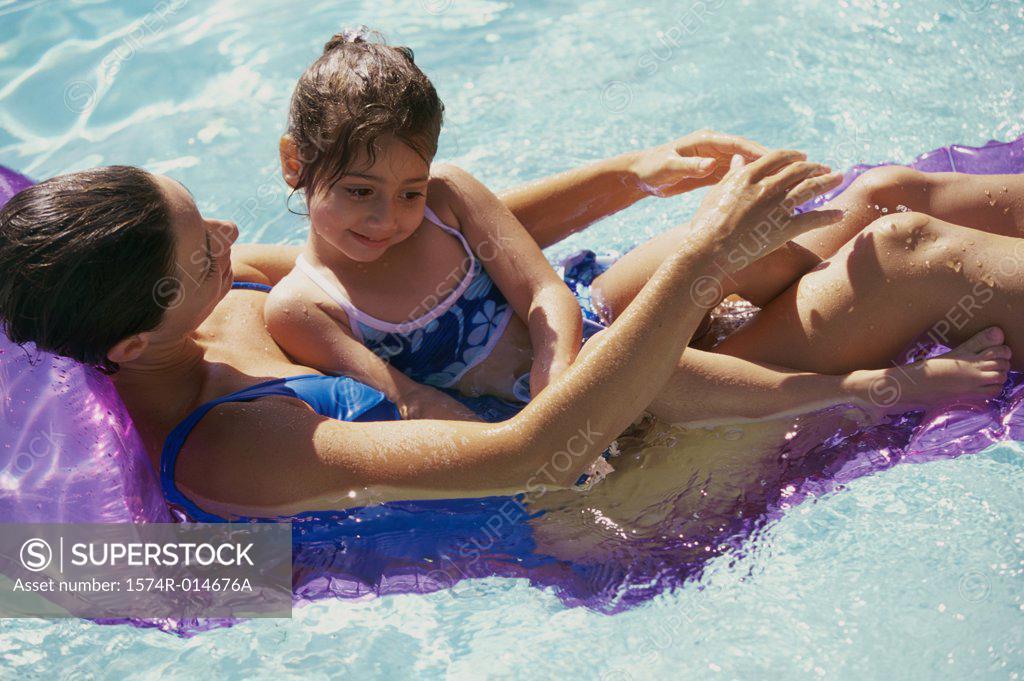 Stock Photo: 1574R-014676A High angle view of a mother with her daughter on a pool raft in a swimming pool