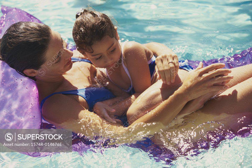 Stock Photo: 1574R-014676E High angle view of a mother with her daughter on a pool raft in a swimming pool
