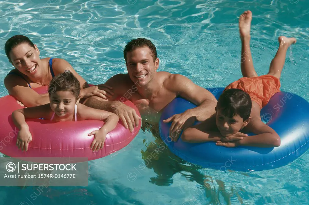 Portrait of a young couple in a swimming pool with their son and daughter