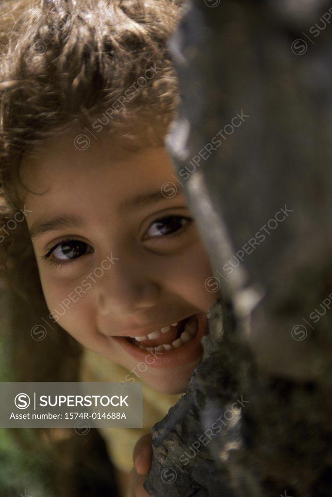 Stock Photo: 1574R-014688A Portrait of a girl hiding behind a rock