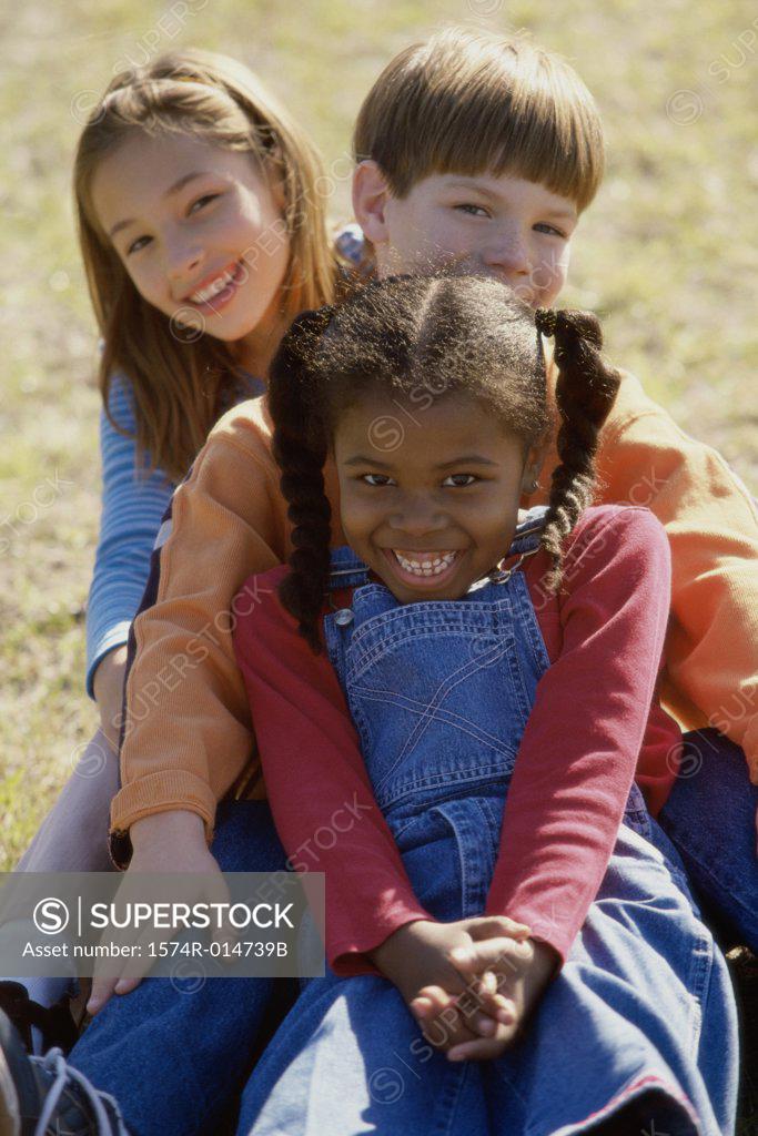 Stock Photo: 1574R-014739B Portrait of two girls and a boy sitting on a lawn