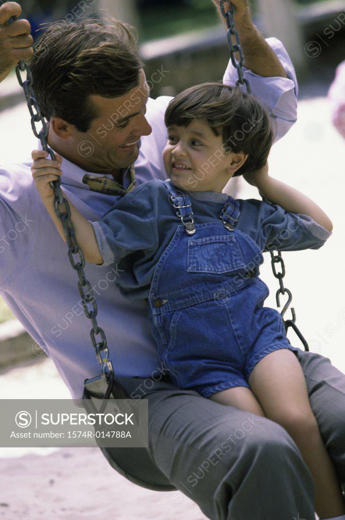 Stock Photo: 1574R-014788A Close-up of a father sitting on a swing with his son