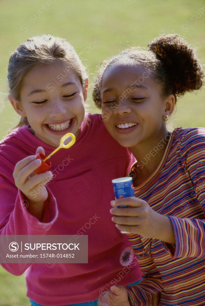 Stock Photo: 1574R-014852 Close-up of two girls holding a bubble wand and smiling