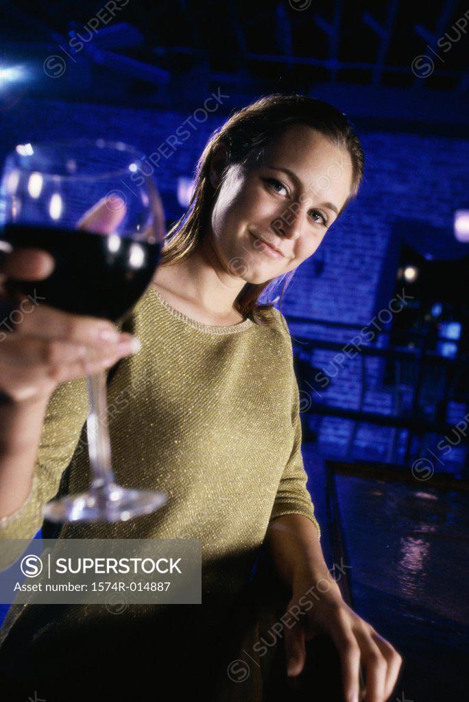 Stock Photo: 1574R-014887 Portrait of a young woman offering a glass of red wine