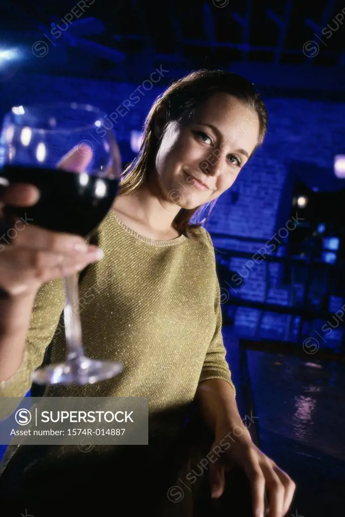Portrait of a young woman offering a glass of red wine