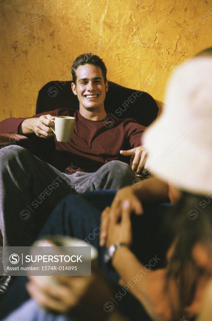 Stock Photo: 1574R-014895 Young man sitting in a restaurant and holding a cup of coffee