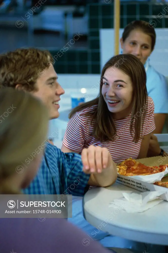 Three teenage girls and a teenage boy smiling in a restaurant