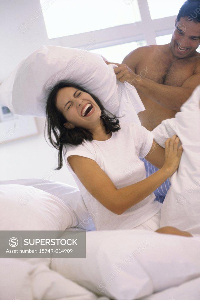 Stock Photo: 1574R-014909 Young couple having a pillow fight in bed