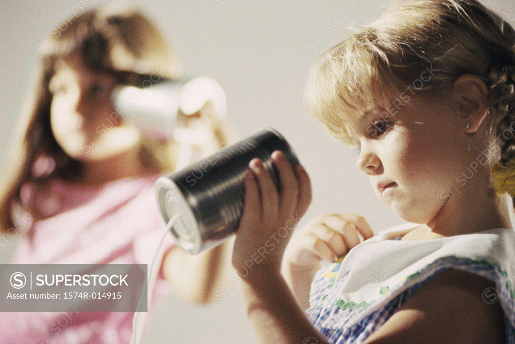 Stock Photo: 1574R-014915 Two girls playing with a tin can phone