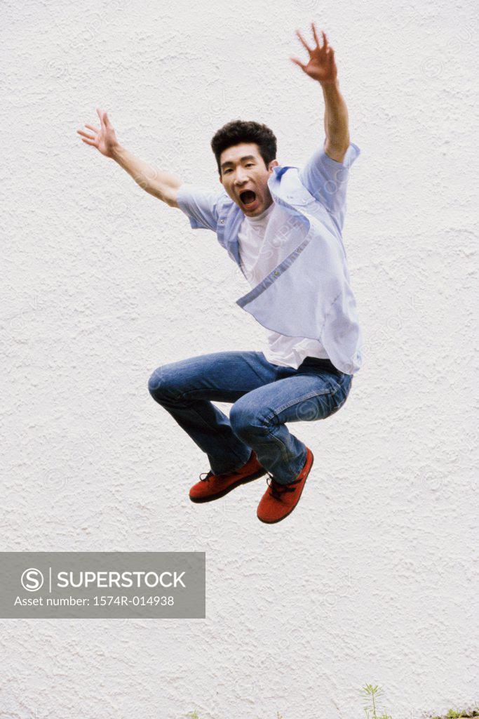Stock Photo: 1574R-014938 Young man jumping with his arms outstretched