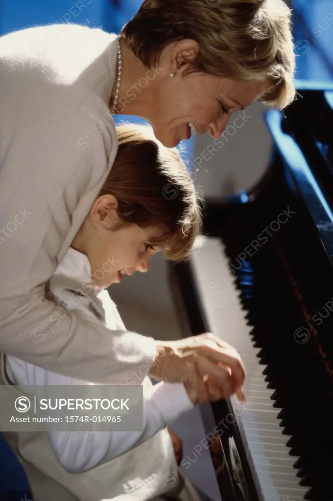 Side profile of a grandmother teaching her granddaughter to play the piano