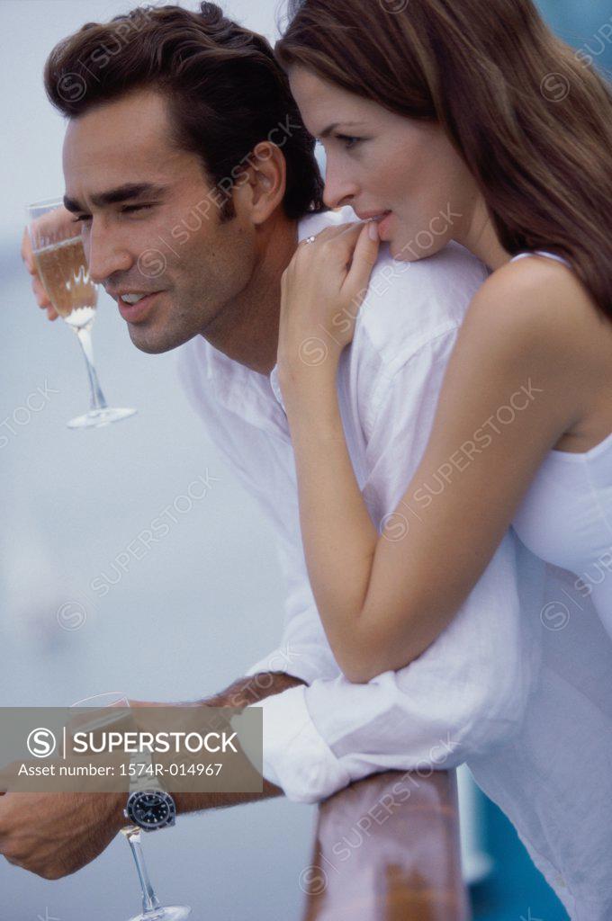 Stock Photo: 1574R-014967 Side profile of a young couple holding glasses of white wine on the deck of a cruise ship