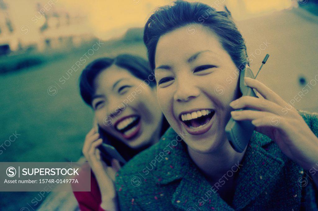 Stock Photo: 1574R-014977A Two young women talking on their mobile phones