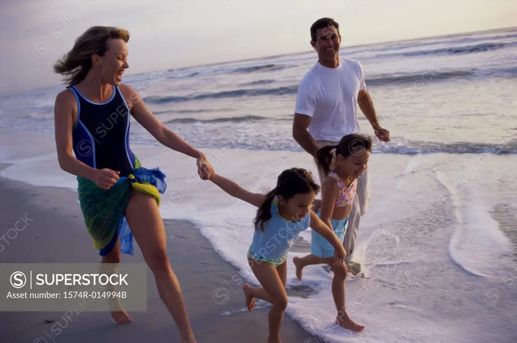 Parents running with their two children on the beach
