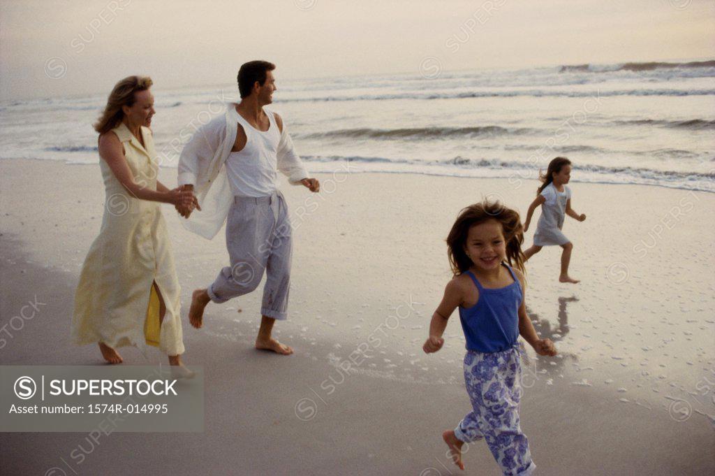 Stock Photo: 1574R-014995 Parents and their two daughters running on the beach