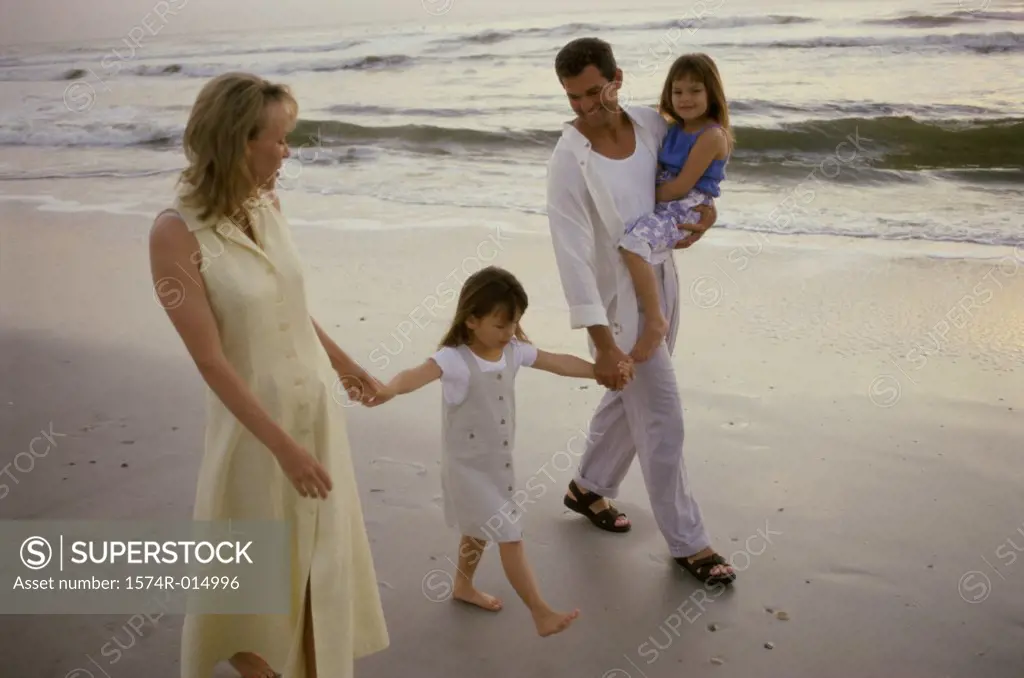 Parents and their two daughters walking on the beach