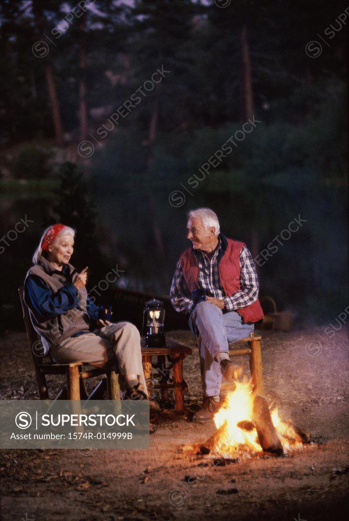 Stock Photo: 1574R-014999B Senior couple sitting near a campfire talking to each other