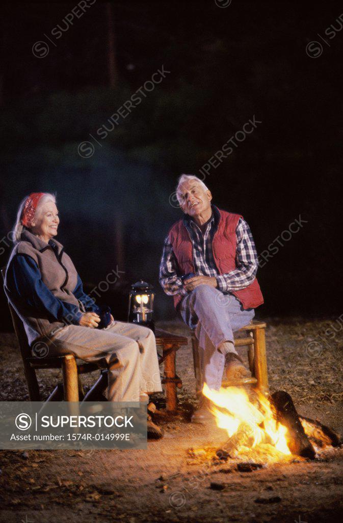 Stock Photo: 1574R-014999E Senior couple sitting near a campfire talking to each other