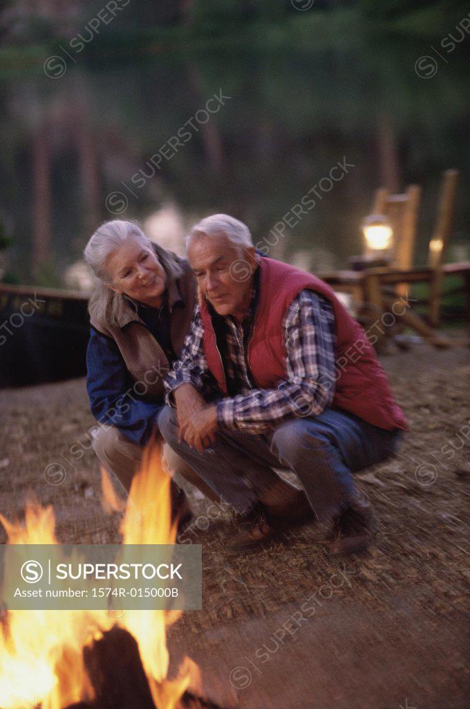 Stock Photo: 1574R-015000B Senior couple crouching and singing near a campfire