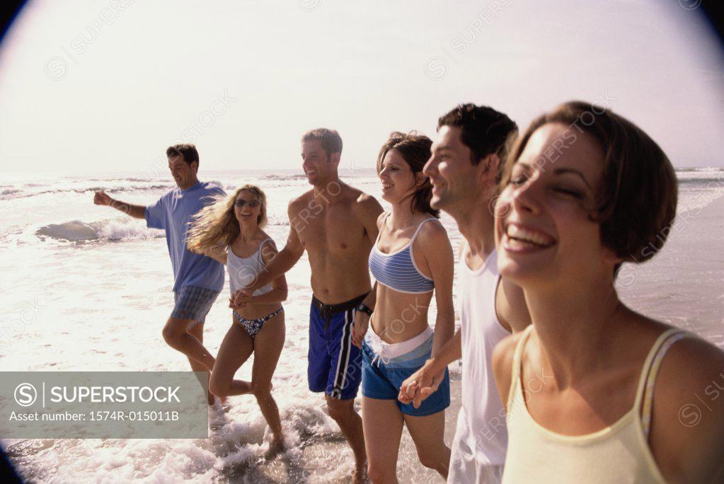 Stock Photo: 1574R-015011B Three young couples holding hands walking on the beach