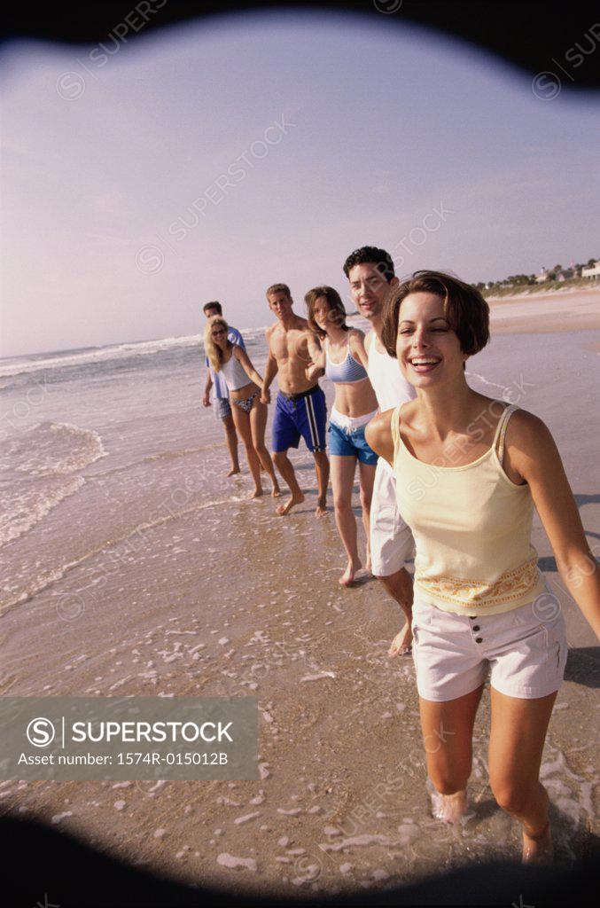 Stock Photo: 1574R-015012B Three young couples holding hands walking on the beach
